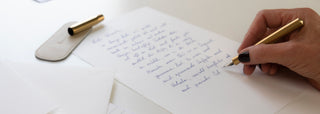 ein weißer Briefbogen aus Büttenpapier wird per Hand mit Füller beschrieben