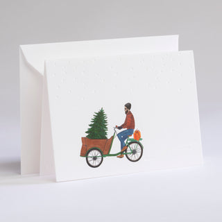 Lastenradfahrer transportiert einen Christbaum